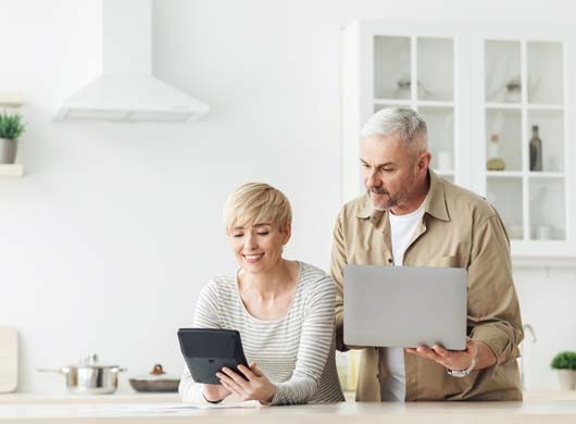 Manage finances bills tax, planning, consider budget. Smiling adult couple with laptop and calculator talk, doing paperwork together at home, discuss family mortgage loan money payment in kitchen