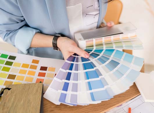 Close-up of architect woman choosing samples of wall paint. Interior designer looking at color swatch for creating project. House renovation, architecture and interior design concept.